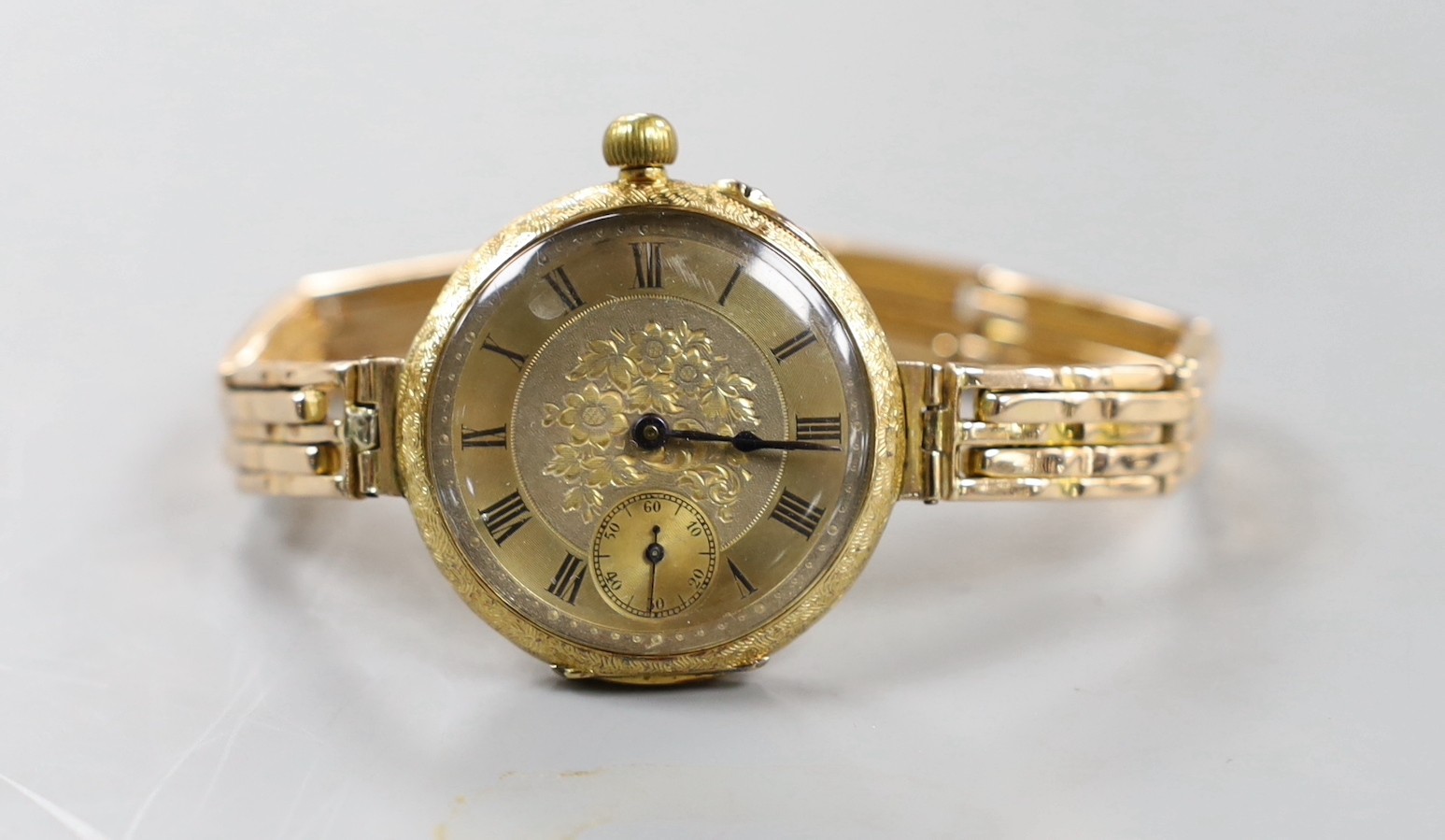 An early 20th century engraved 18ct gold fob watch, now converted to a wrist watch on a later expanding yellow metal bracelet